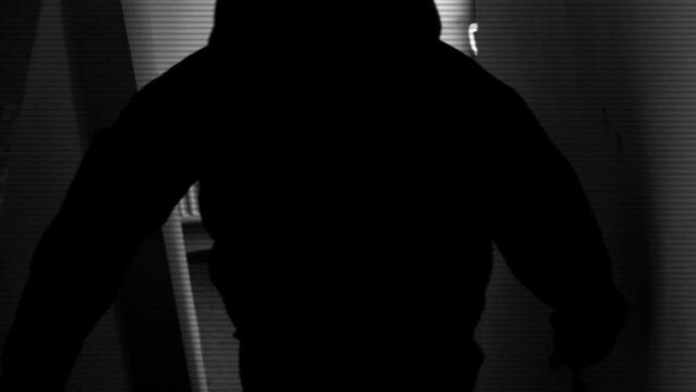 A scary amateur video of a man or a maniac with a knife, or an ax man climbing the steps in the dark. Horror, mysticism, crime, murderer.