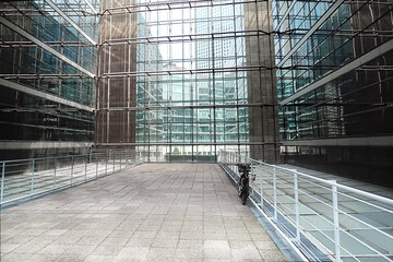 skyscraper inside: light courtyard with a parked bicycle; view of the modern business district outside the large windows (La Défense, Paris, France)