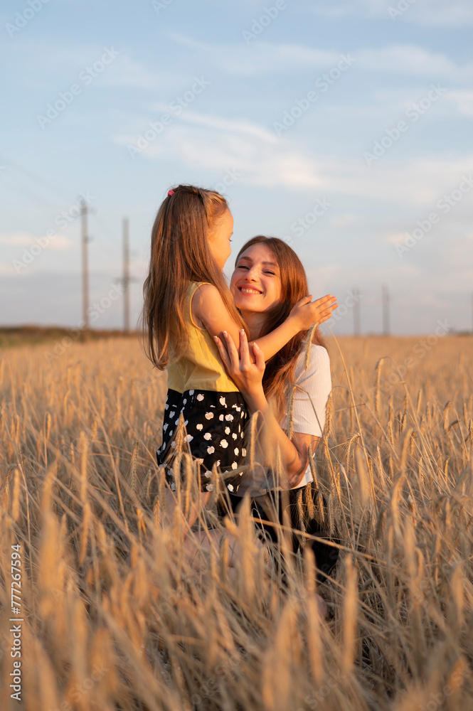 Wall mural A mother and his daughter in field at sunset	