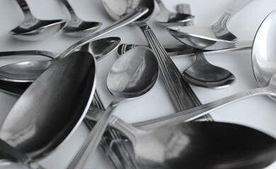 Big And Small Metallic Spoons Scattered On White