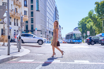 fashionable woman in a tight dress and high heels crossing a crosswalk in the city