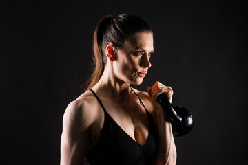 Tough fitness female model with kettle bell on grey dark yellow red background.