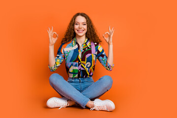 Photo of lovely pretty cheerful girl wear trendy print clothes okey gesture isolated on vivid orange color background