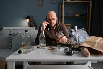 Drunk man at home holding whiskey bottle indoors in alcoholism problem, alcohol abuse and addiction...