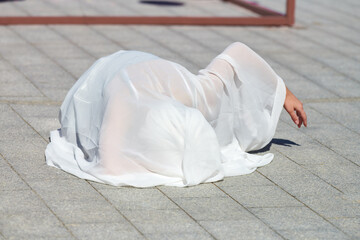 Female performer covered in white silk scarf waving gracefully, female outdoor dance performance on...