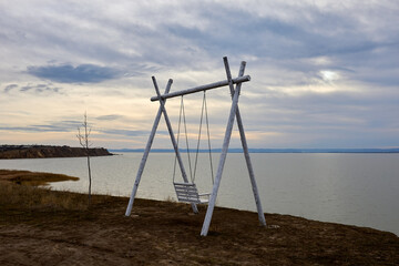 Swing on a cliff. View of the lake at winter sunset