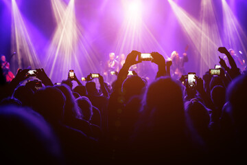 Holding a phone and taking photos of the concert. Concert background.