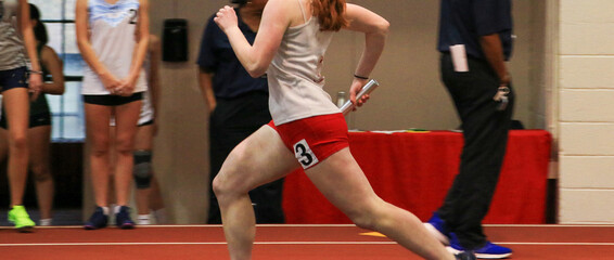 female runner running fast on an indoor track