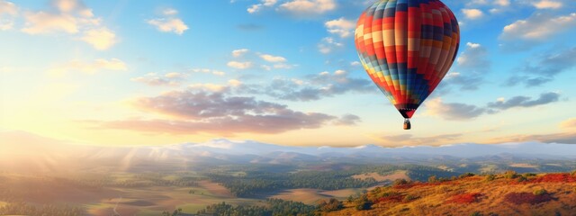Hot air balloon over a field and a beautiful landscape with blue sky, travel and joy of life