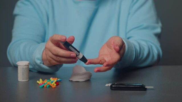 Diabetic aged woman patient suffering sugar diabetes measures blood glucose level with a glucometer at home. Health care, diabetic lifestyle