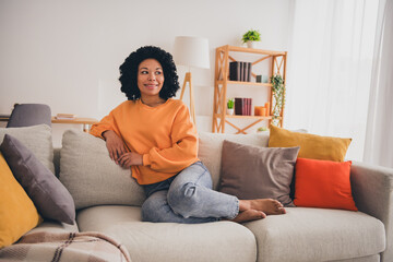 Photo portrait of lovely young lady sit sofa look empty space dressed casual orange clothes cozy day light home interior living room