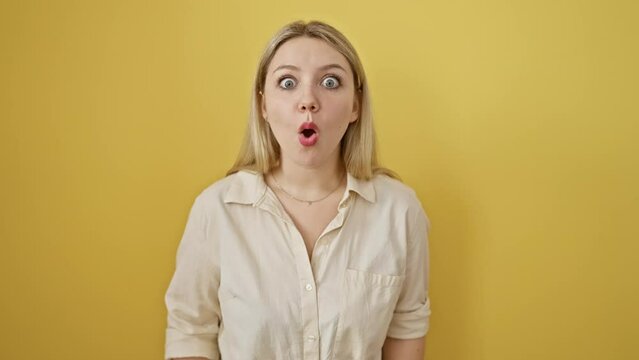 Shocked young blonde woman with open mouth expressing surprise, fear and amazement. surprised and scared expression on her face on isolated yellow background.