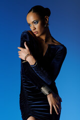 Young African American female model posing gracefully in a stunning blue dress.