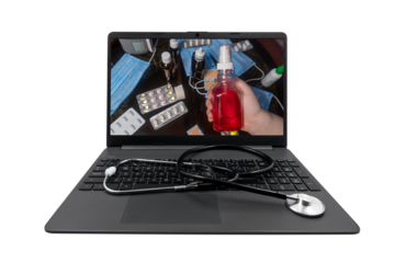 On the laptop screen - a red medical spray in the hand on the background of a table with medicines