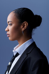 Young African American woman in a suit and tie gazes thoughtfully to the side.