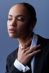 Young African American woman exudes confidence in a tailored suit and statement necklace.