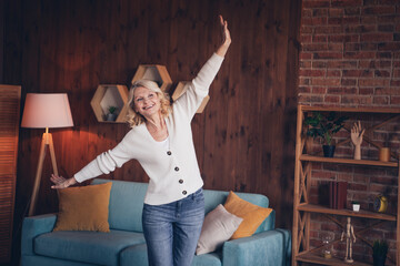 Photo portrait of lovely retired woman raise hands dance have fun dressed casual outfit cozy home interior living room in brown warm color