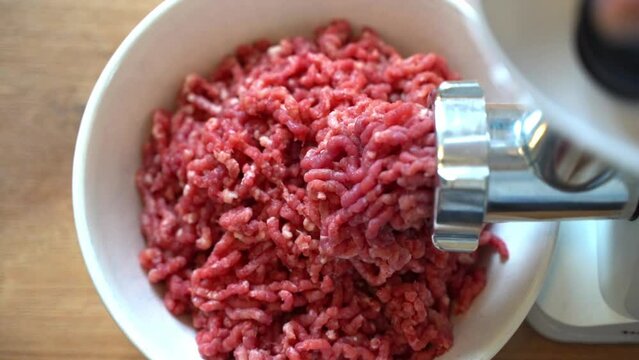 Minced meat in a meat grinder. Preparing fresh ground beef for cutlets in the kitchen.