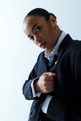 Young African American woman in her 20s adjusting her tie in a studio setting.