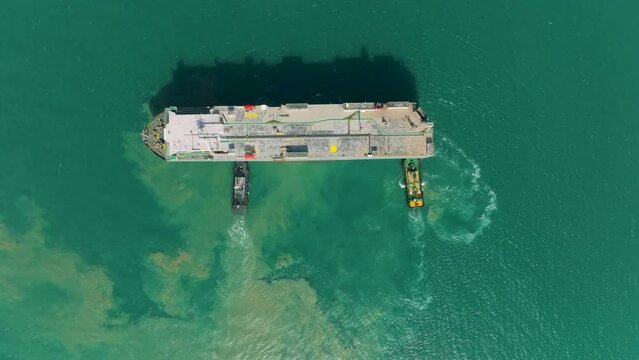 Aerial view Tug boat pushing Large RoRo (Roll on Roll off) to loading dock or quayside for carrier vessels convey cars and trucks into and out of the world market. 4k video