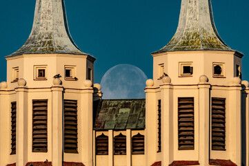księżyc w pełni zachodzący za dwoma wieżami kościoła - obrazy, fototapety, plakaty
