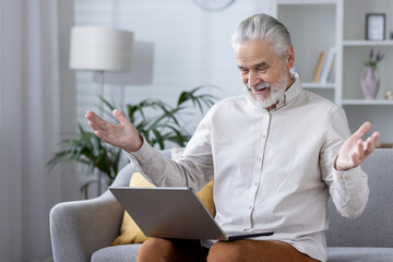 Senior man with laptop having unexpected moment at home