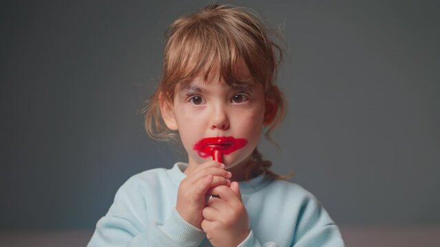 Portrait of cute little girl trying on lipstick for the first time. Happiness, fun, entertainment