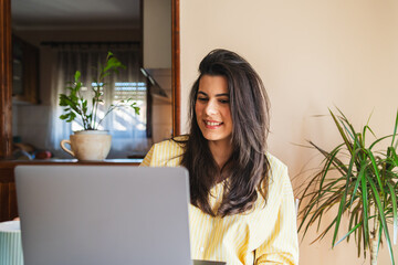 One young girl or woman is using her laptop to work from home in the morning while drinking coffee