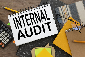 INTERNAL AUDIT glasses on a yellow notepad on a gray folder. text on a notepad