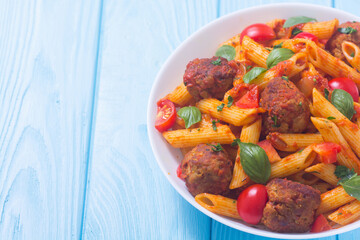 Italian penne pasta with meatballs and tomatoes