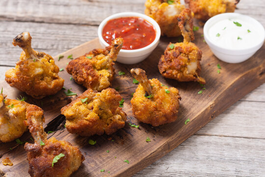 Chicken wings nuggets with sauces on wooden background .