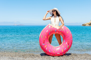 Happy woman with inflatable donut on tropical beach. Summer vacation concept.