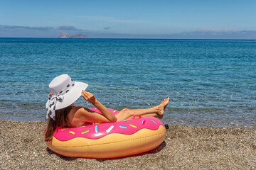 Happy woman with inflatable donut on a tropical beach. Summer vacation concept.