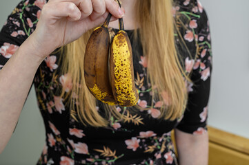 Kobieta trzyma marne, małe, brzydkie banany w dłoni  - obrazy, fototapety, plakaty
