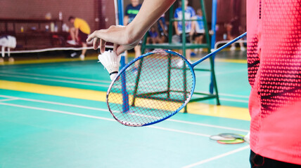 The badminton player holding a white shuttlecock and racket