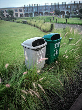 organic and non organic trash bin with do not littering sign on the public park indonesia surrounded by tall long green grasses Stipa tenufolia gigantia 