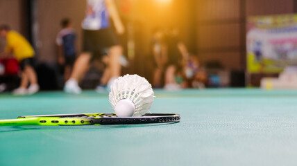 White badminton shuttlecocks and badminton rackets on green floor indoor badminton court soft and selective focus on shuttlecocks and the rackets