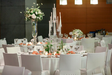 White color wedding table decorated with decorative and elegant for wedding. There are flowers, candles and serving plates on the wedding table.