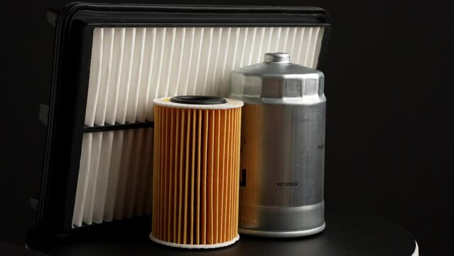 Car parts: oil filter, air filter and fuel filter rotate slowly on black background, close-up. Auto parts replacement concept, car maintenance, car service.