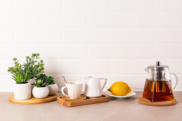 Beautiful kitchen background with glass teapot of fragrant tea, cup and lemon on tray. Front view....