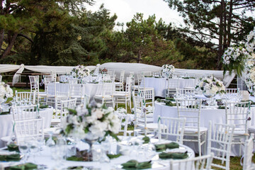 White color wedding table decorated with decorative and elegant for wedding. There are flowers, candles and serving plates on the wedding table.