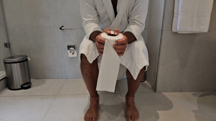 Man sits on toilet with toilet paper and suffers from diarrhea constipation concept 