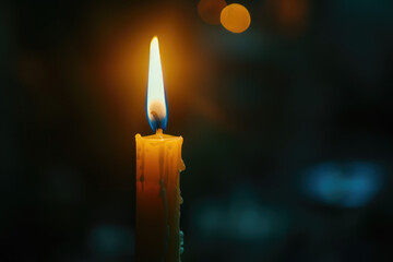One candle burns on a dark background with copy space. A symbol of memory and sorrow, orange fire in memory of the dead.