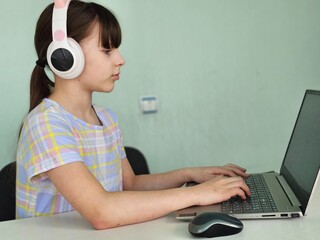 Little Girl Using Laptop and Headphones at Desk