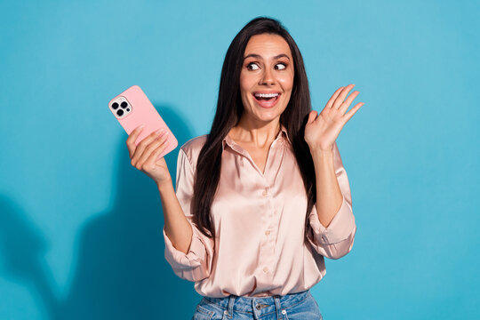 Photo of excited impressed woman wear silky blouse texting sms modern gadget looking empty space isolated blue color background