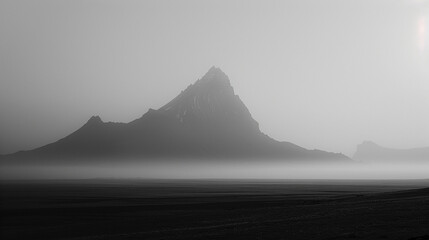 The dramatic silhouette of a solitary mountain rising from the plains, shrouded in mist at dawn.