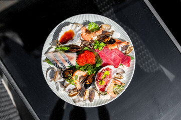 A sumptuous seafood platter featuring oysters, shrimp, mussels, sashimi, and garnishes elegantly...