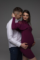 pregnant couple on a grey background in a studio