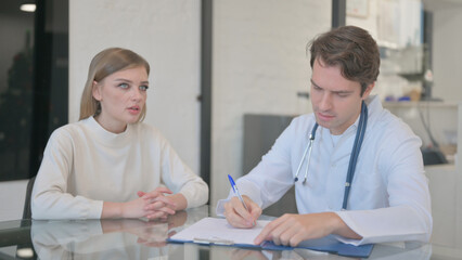 Fototapeta premium Male Doctor Writing Medication for Female Patient