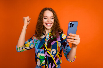 Photo of charming cheerful girl blogger wear stylish print clothes celebrate success isolated on vibrant orange color background